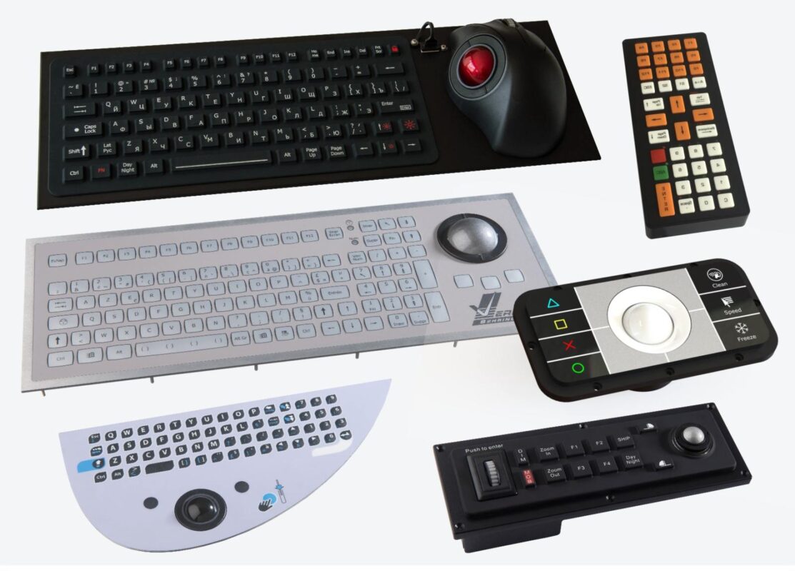 The image depicts a collection of adaptive input devices, including several types of keyboards and trackballs.