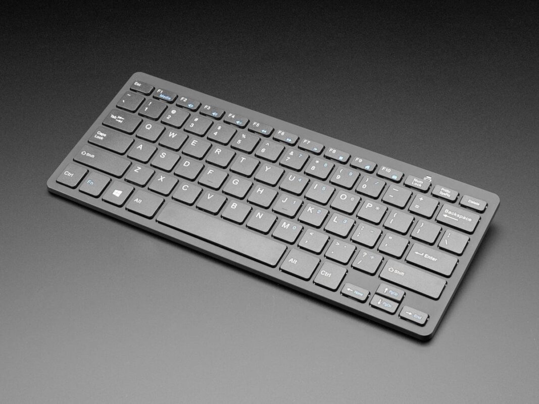 تُظهر الصورة لوحة مفاتيح كمبيوتر صغيرة الحجم وسوداء اللون بتصميم QWERTY قياسي.